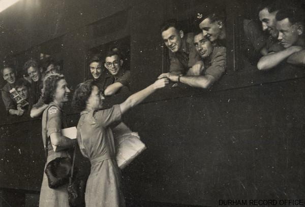 Women’s Voluntary Service volunteers handing out magazines and playing cards before the train left Pusan, 1st Battalion DLI, September 1952. Image © Durham Record Office (D/DLI 7/915/1(14))